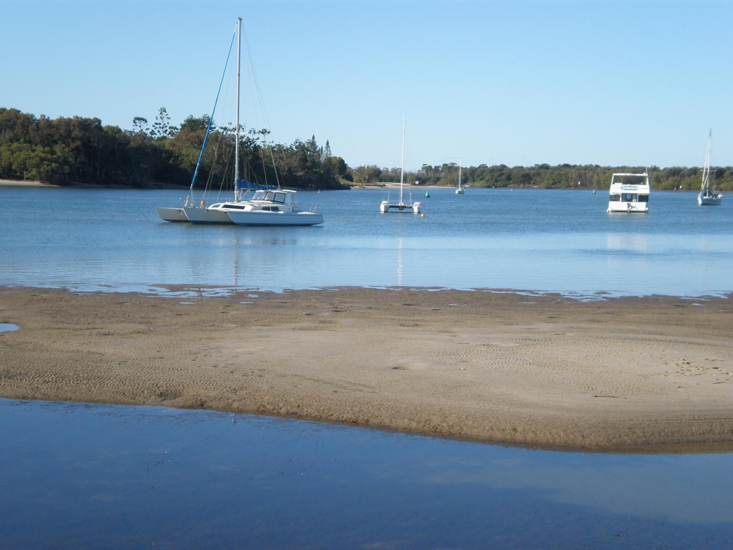 A calm bay with several boats anchored near the shore.
