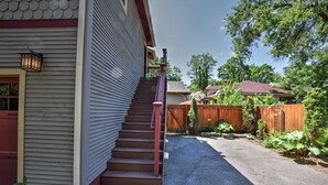 A residential property with a covered outdoor staircase, a wooden fence, and a garden area.