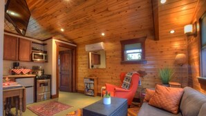 A cozy cabin interior with wooden walls, a kitchen area, a sofa, and a coffee table.