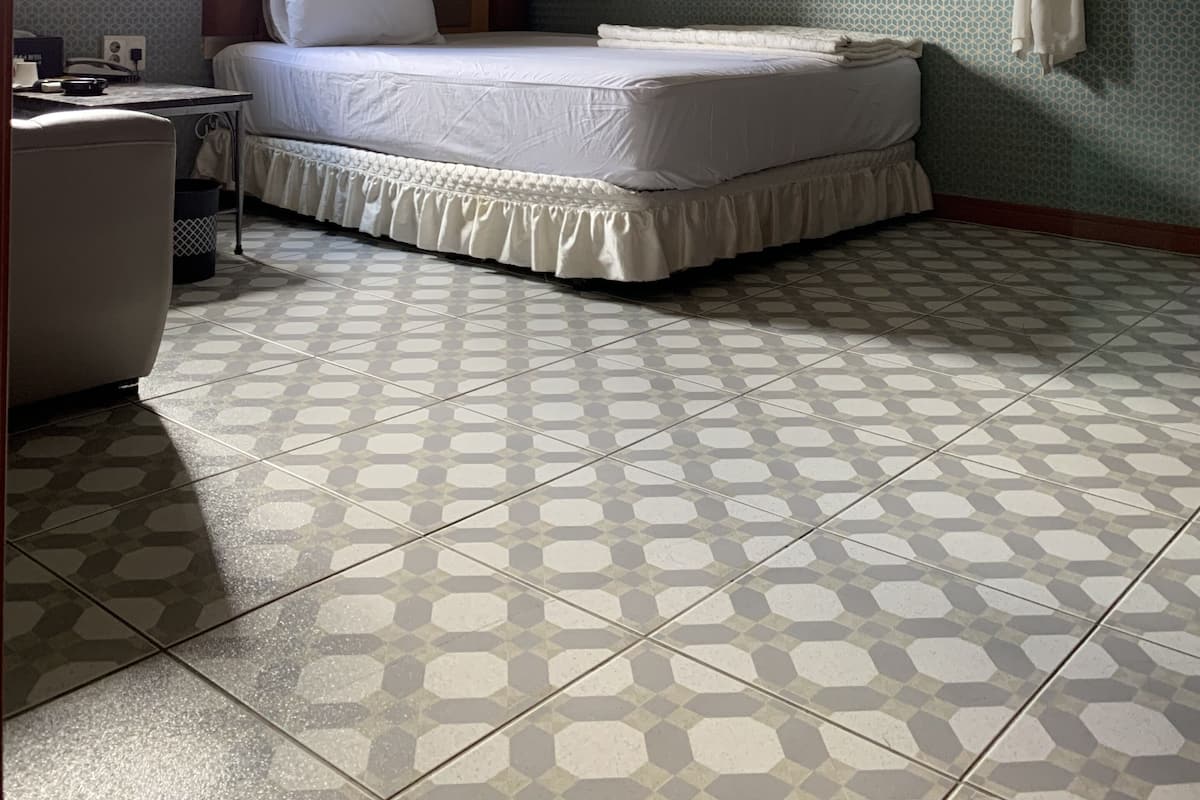 Une chambre d’hôtel avec un lit, une chaise, une robe accrochée au mur et une fenêtre.
