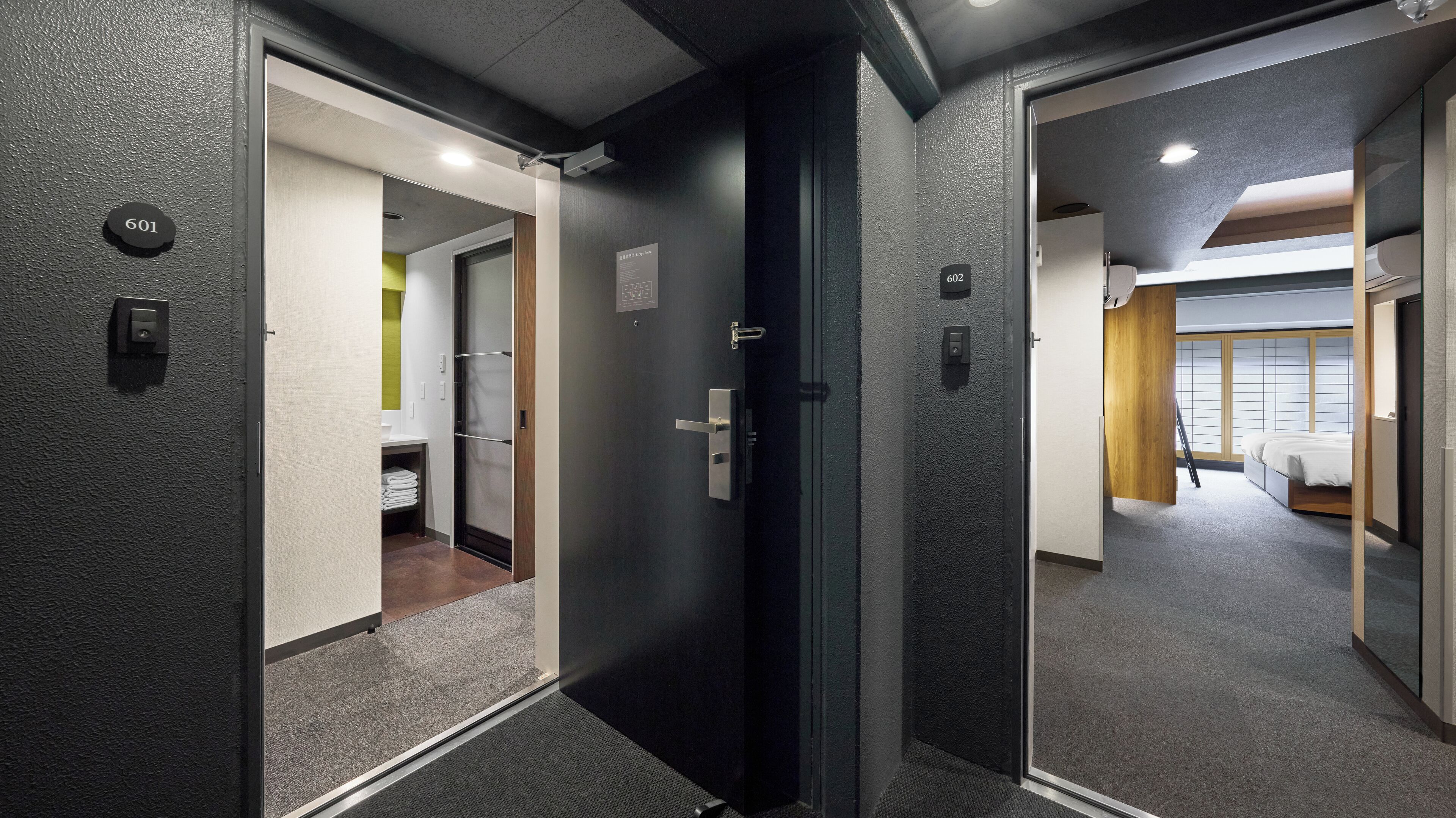 A hotel corridor with doors numbered 601 and 602, leading to rooms with beds and a visible bathroom.