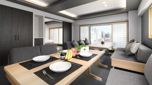 Un espace de repas moderne avec une table en bois, des canapés gris et une vue sur la ville grâce à de grandes fenêtres.