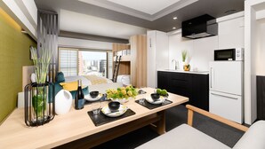 Une cuisine moderne avec un coin repas, comprenant une table en bois pour quatre personnes, un réfrigérateur et un four à micro-ondes.