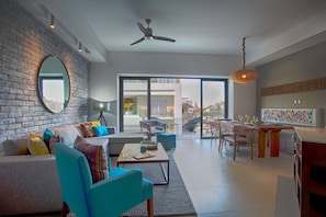 A modern living room with a sofa, chairs, a coffee table, and a dining area with a table and chairs.