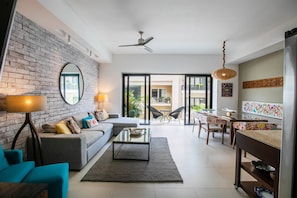A modern living room with a sofa, coffee table, and a dining area with chairs and a table.