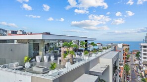 A rooftop terrace with outdoor seating, a pool, and a view of the sea.