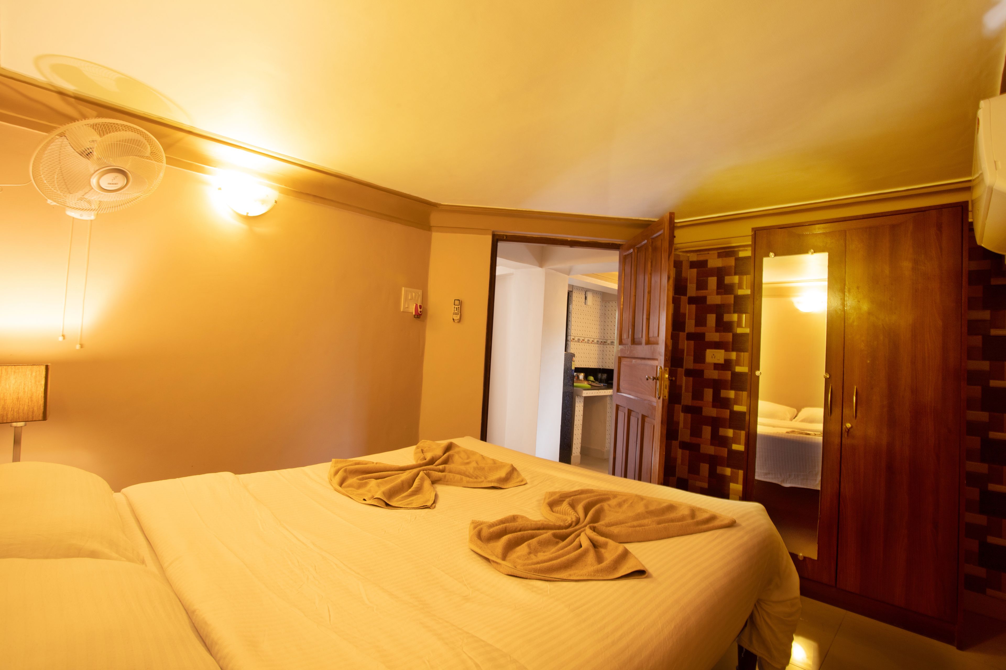 Hotellihuone, jossa on sänky, tuuletin ja vaatekaappi.