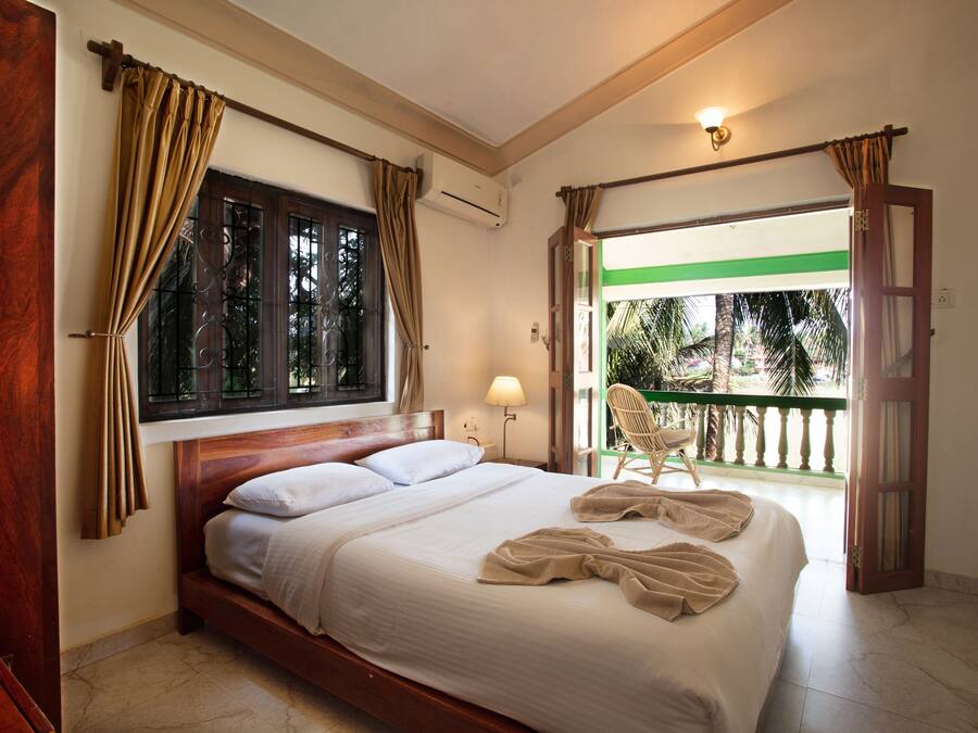 Una habitación de hotel con cama, cortinas, ventana, una silla y aire acondicionado.