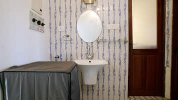 A bathroom with a sink, mirror, and a door.