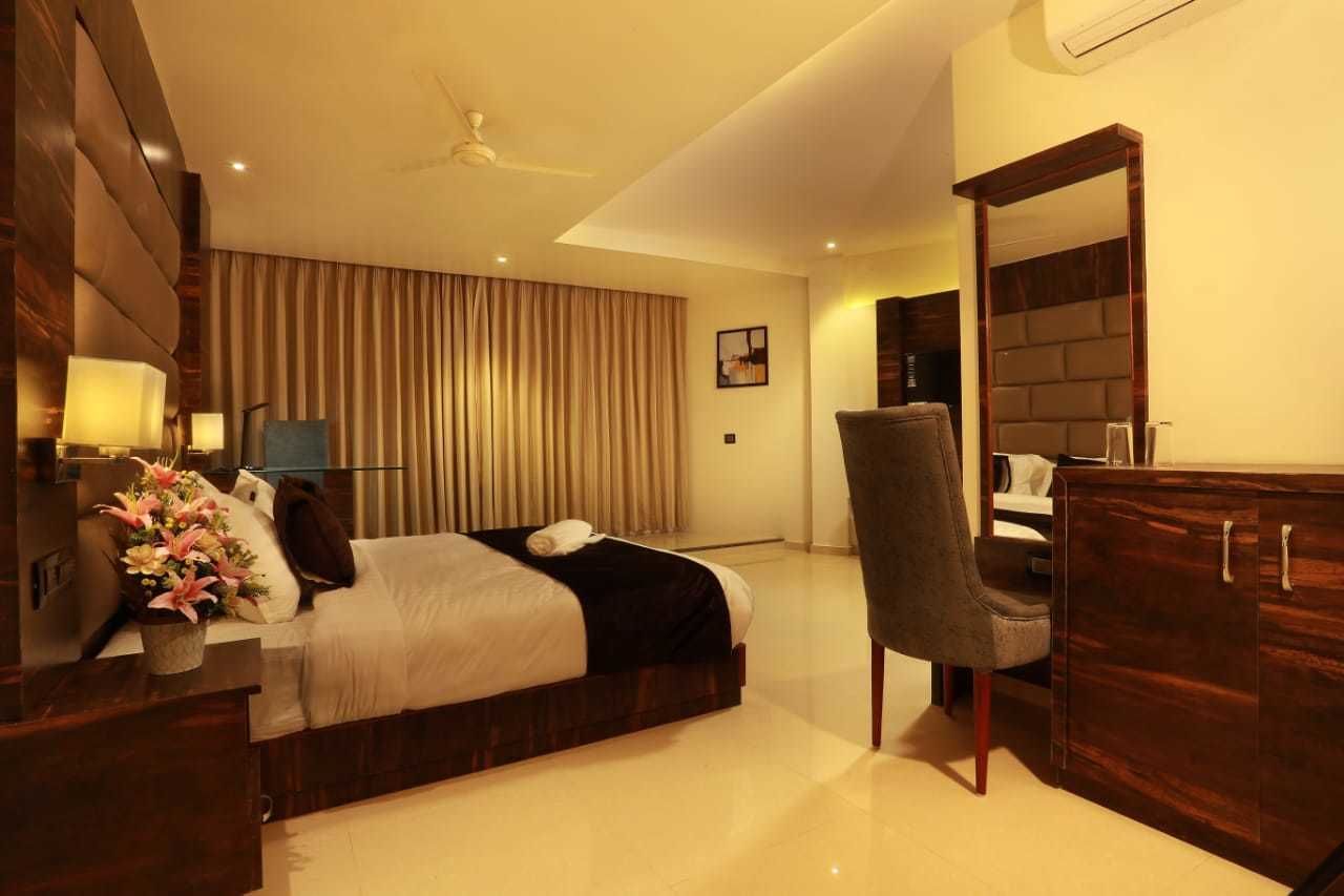 Una habitación de hotel moderna con una cama grande, un escritorio, una silla y un armario.