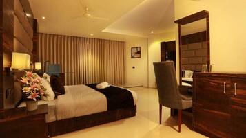 Una habitación de hotel moderna con una cama grande, un escritorio, una silla y un armario.