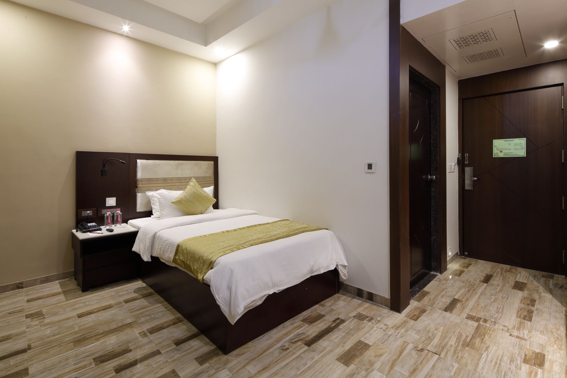 Habitació d'hotel amb un llit, una taula de nit i una porta.