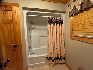 A bathroom with a bathtub, shower, and wooden door.
