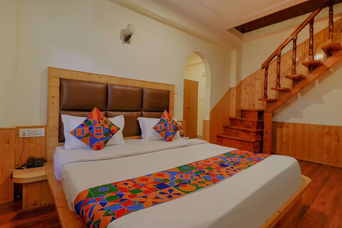 Una cama grande con cabecera de madera, un corredor de cama colorido y dos almohadas con diseños geométricos.