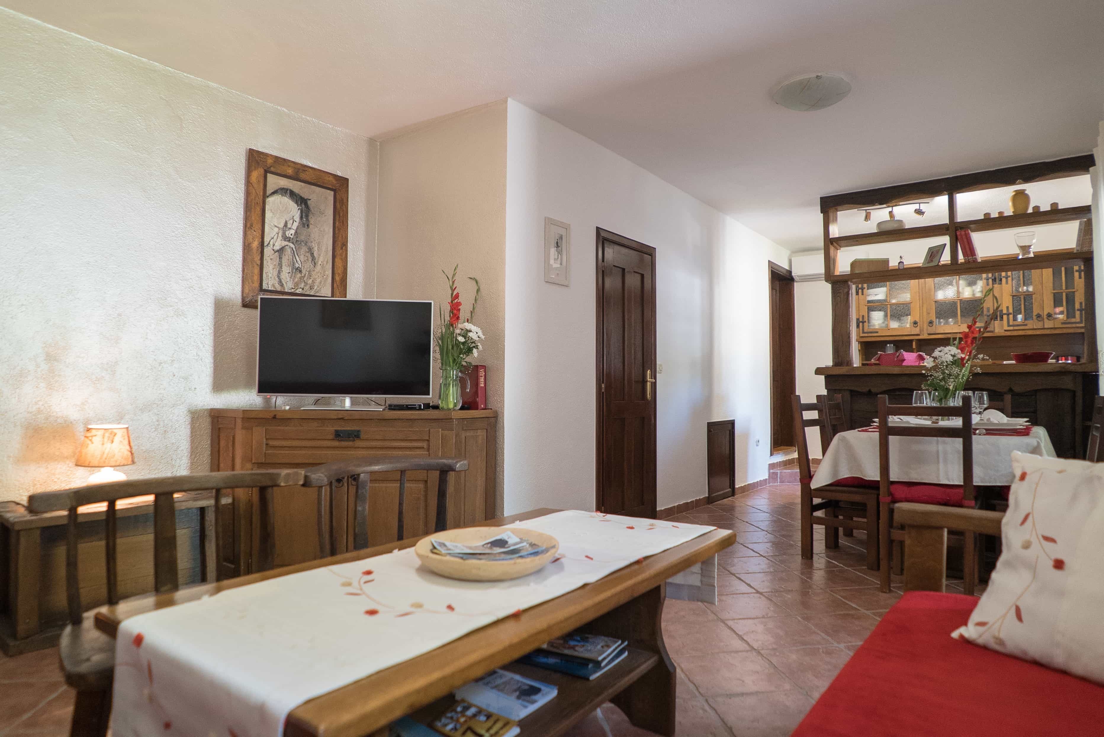 A dining area with a wooden table, chairs, and a television on a cabinet.
