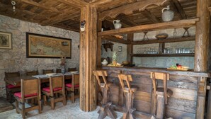 Un intérieur rustique avec des murs en pierre, un bar en bois et un espace repas agrémenté de chaises et de tables en bois.