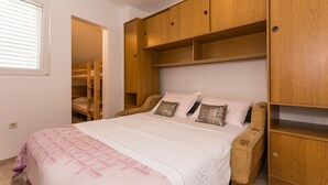 Une chambre à coucher avec un lit, une armoire en bois et une chaise.