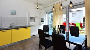Una cocina moderna con armarios amarillos, encimera negra y comedor con mesa de vidrio y sillas negras.