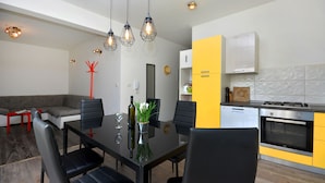 Una cocina moderna con comedor, que incluye una mesa de comedor negra, sillas e iluminación colgante.