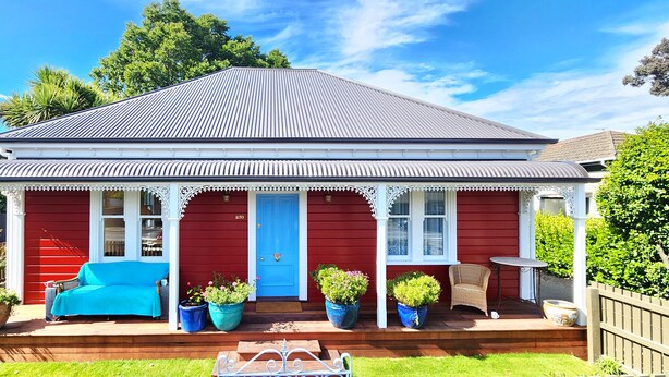 A red house with a blue door, a porch with a blue sofa, and potted plants. - Rewa House ~ city home, 3 bedrooms, walk to CBD (Christchurch)