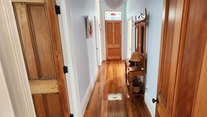 A hallway with wooden doors, a wooden bench, and a small table with a lamp. - Rewa House ~ city home, 3 bedrooms, walk to CBD (Christchurch)