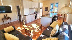 A modern living room with a sofa, coffee table, and a TV mounted on the wall. - Rewa House ~ city home, 3 bedrooms, walk to CBD (Christchurch)