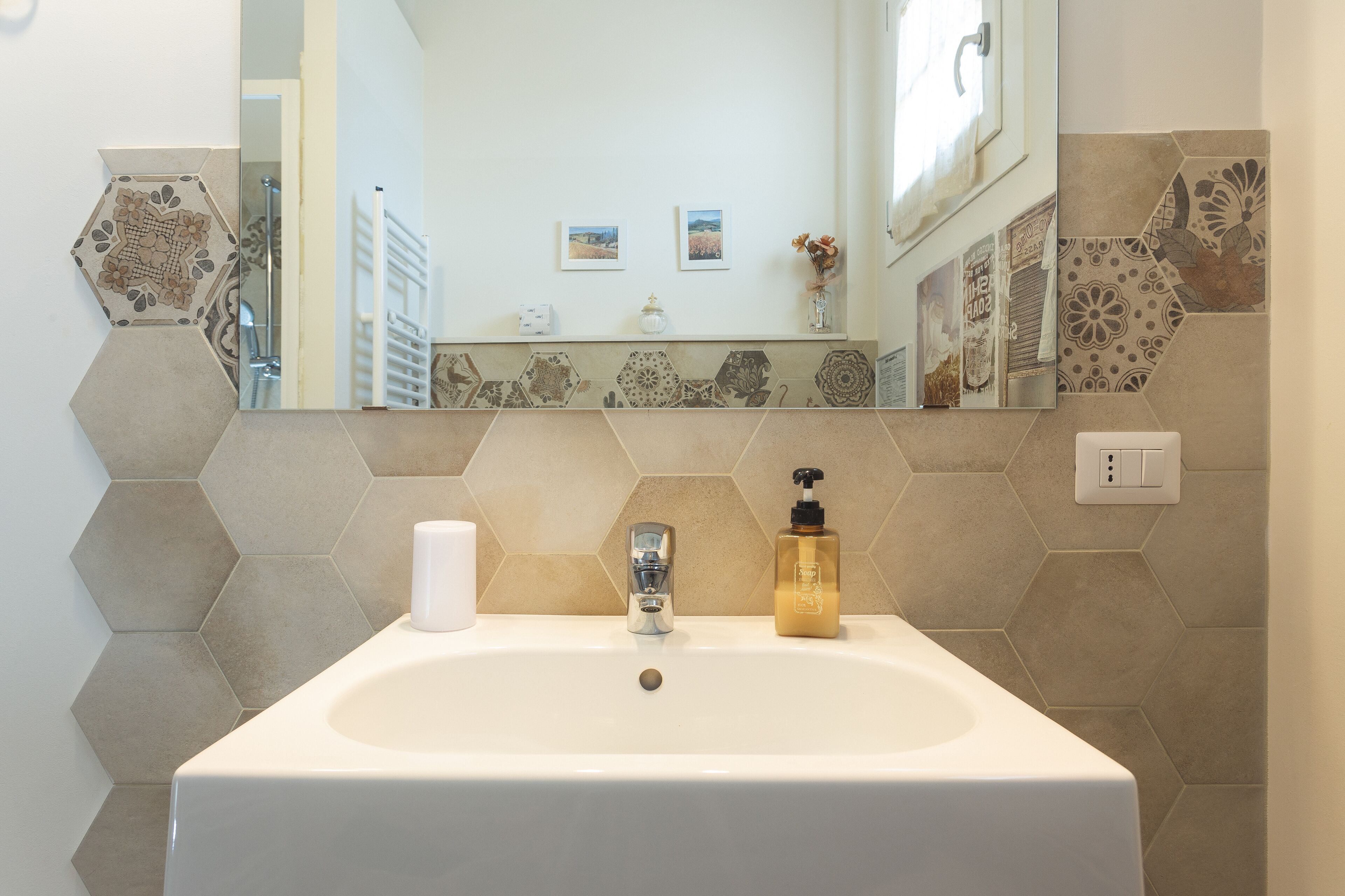 A bathroom with a white sink, a chrome faucet, and a mirror above it.