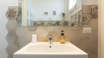 A bathroom with a white sink, a chrome faucet, and a mirror above it.