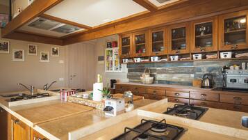 Una cocina con armarios de madera, una isla central con estufa y diversos electrodomésticos.