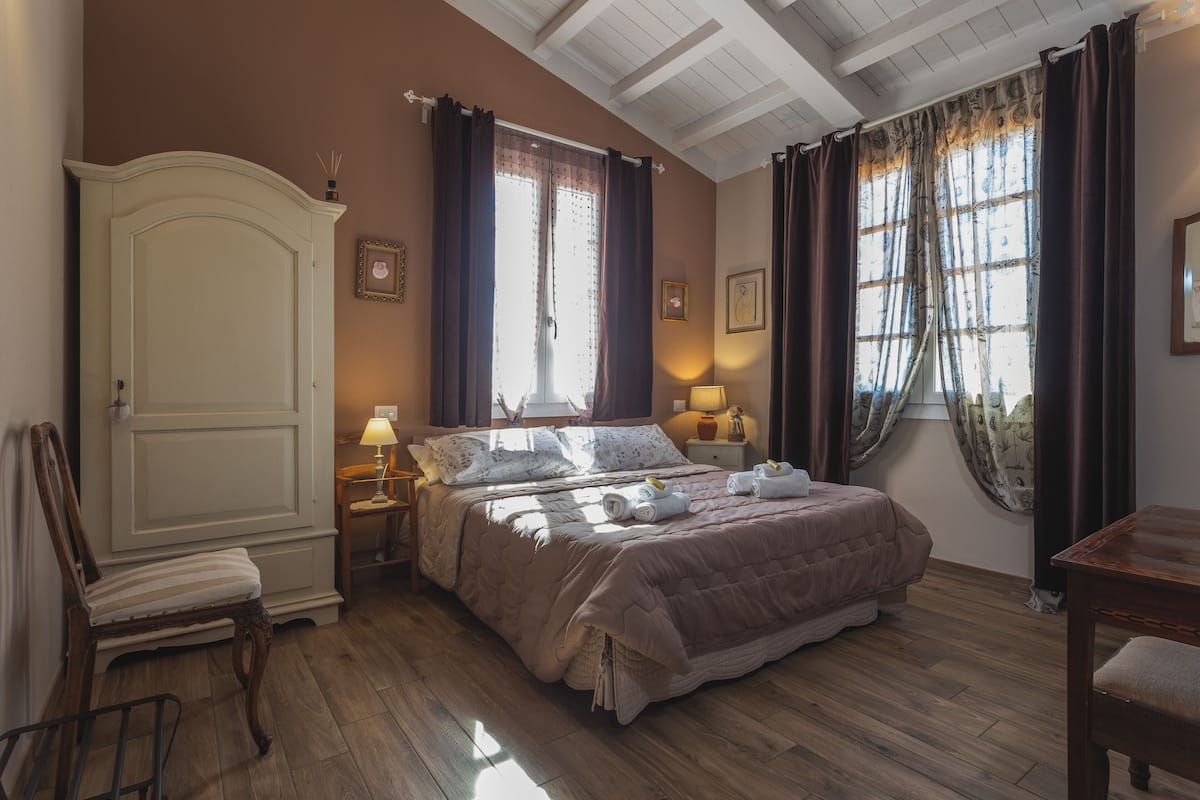 Un dormitorio con una cama grande, un armario, una silla y un escritorio.