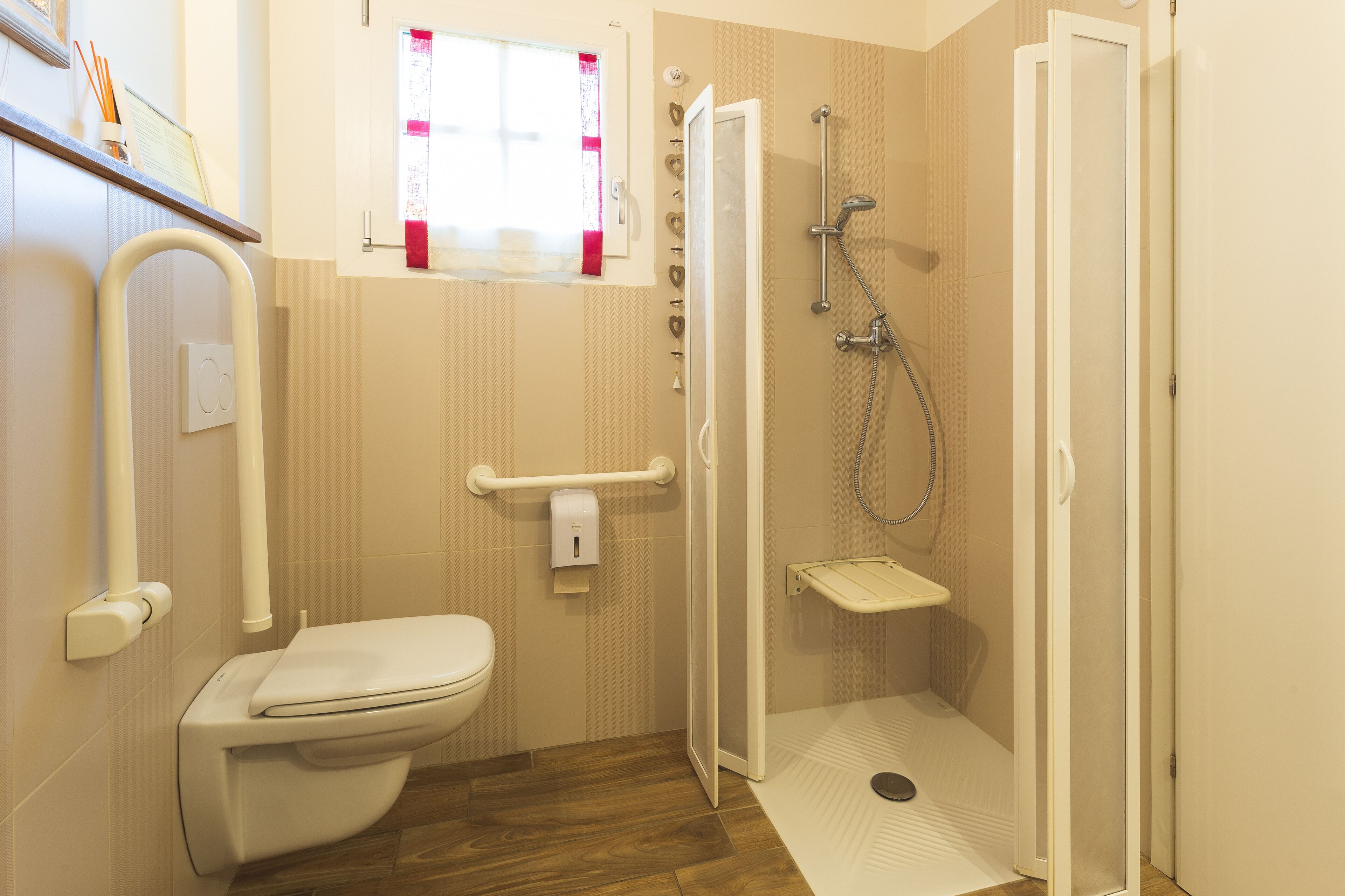 Une salle de bain avec des toilettes, une douche et une fenêtre.