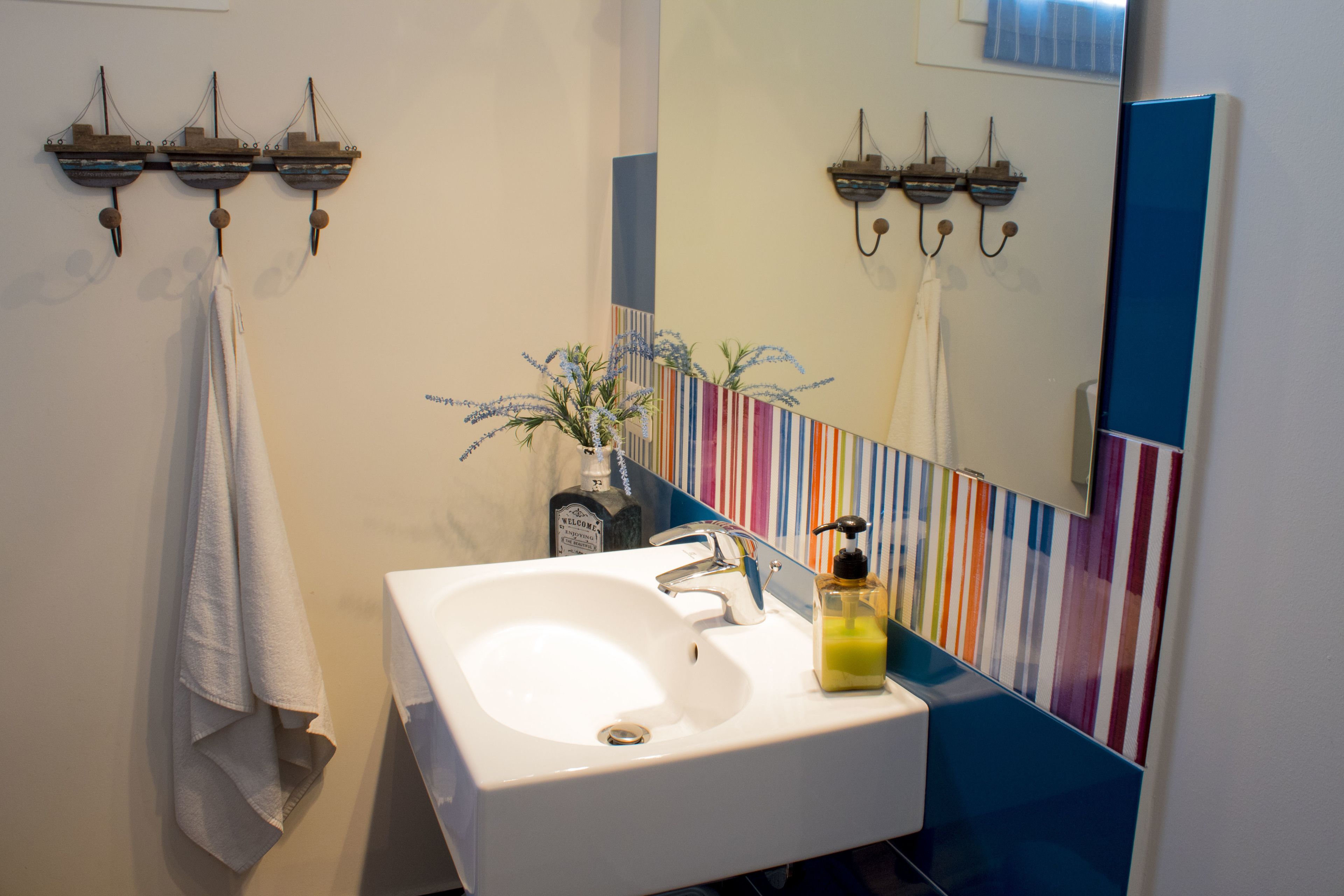 A bathroom with a white sink, a mirror, and a striped wall.