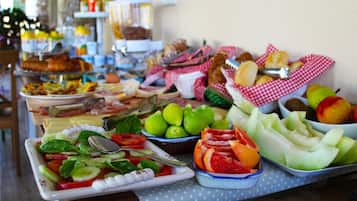 Uma mesa de buffet com diversos alimentos, incluindo frutas, vegetais e doces.