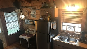 Une cuisine de taille réduite comprenant un réfrigérateur, un évier et un coin repas avec une table et des chaises.