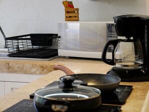Fully equipped kitchen with microwave, coffee maker, and cooking essentials.