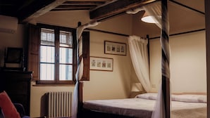 A traditional room with a four-poster bed, a radiator, a window with blinds, and framed pictures on the wall. - Small Apartment With Independent Access  In Beautiful Tuscan Farmhouse (Castelnuovo Berardenga)