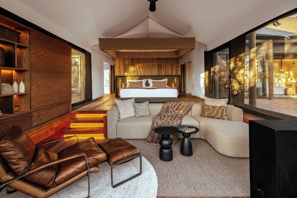 Un dormitorio moderno con una cama grande, un sofá, una mesita de centro y un televisor.