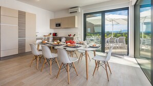 Una cucina moderna con zona pranzo, ampie finestre e vista sull'esterno.