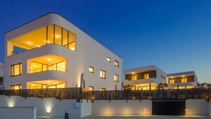 Un edificio moderno a più piani con balconi, ampie finestre e un ingresso con cancello.