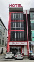 Un hotel con fachada moderna, que destaca un cartel grande con la palabra 'HOTEL' en la parte superior y la señalización 'The Red Hotel' debajo.