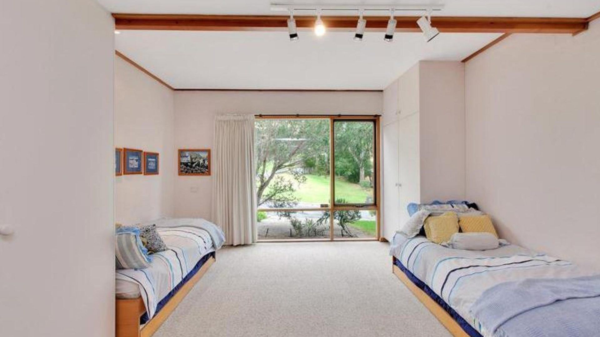 Ein Schlafzimmer mit zwei Betten, einer großen Schiebetür zu einem Garten und einer Decke mit Einbauleuchten.