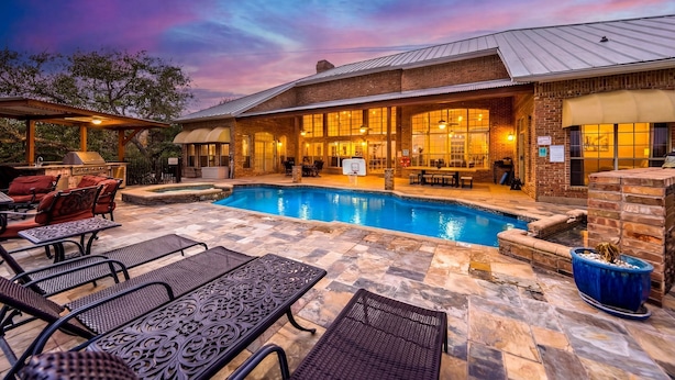 A poolside area with lounge chairs, a basketball hoop, and a covered patio. - Experience Vista Grande: 4600 sq ft. of Luxury - Heatable Pool and City Views (Helotes)
