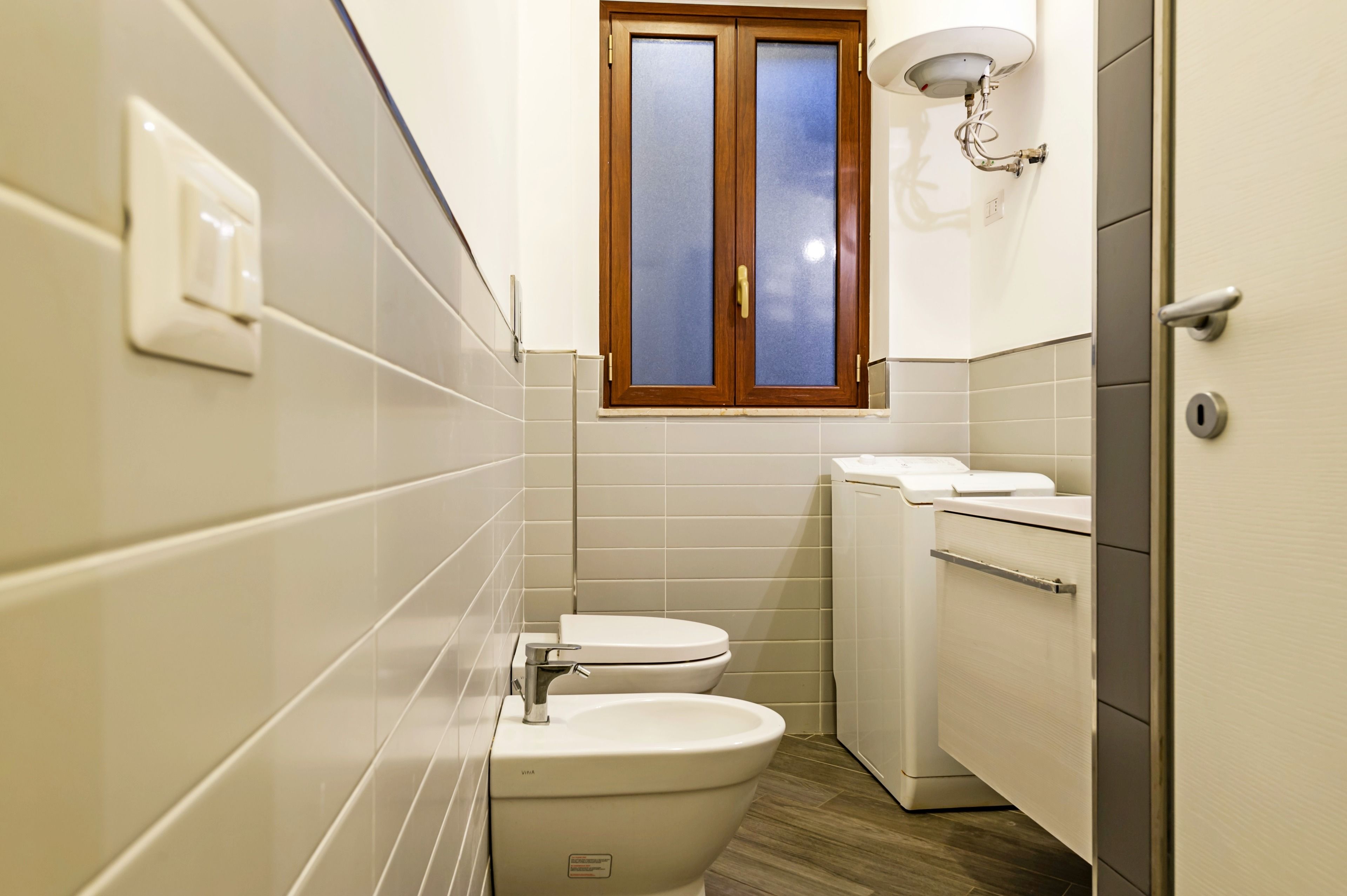 Un baño pequeño con inodoro, bidé y lavadora.