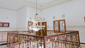 Una habitación amplia con candelabro, puertas de madera y barandilla decorativa.