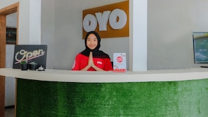 Un mostrador de recepción con un cartel de 'OYO', un letrero de 'Bienvenido' y un folleto informativo.