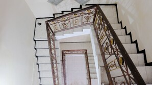 Una escalera con barandilla de metal decorativa y pared de azulejos blancos.