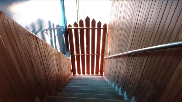Una escalera de madera con barandilla de metal que lleva a un portón.