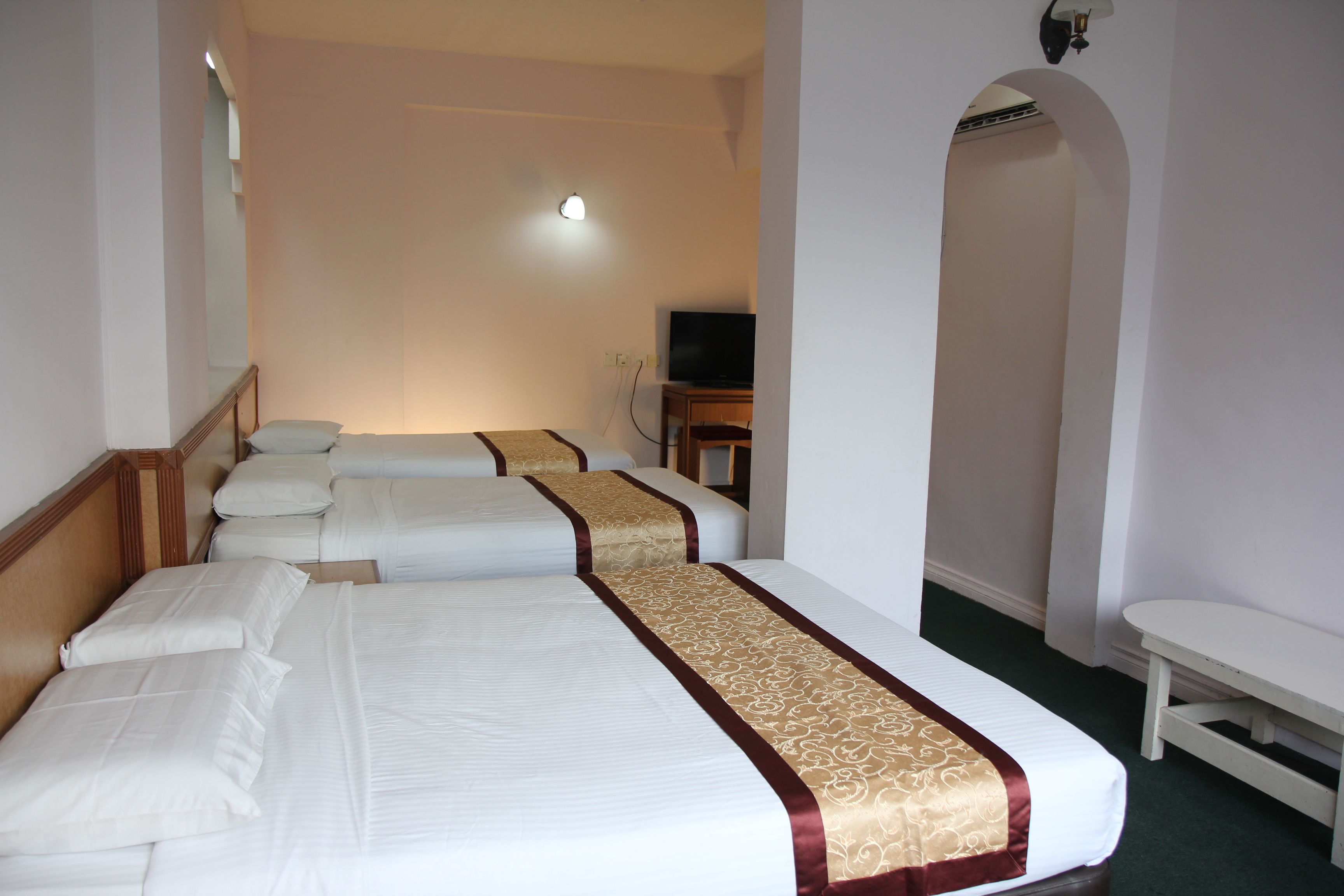 A hotel room with three beds, a television, and a small table.