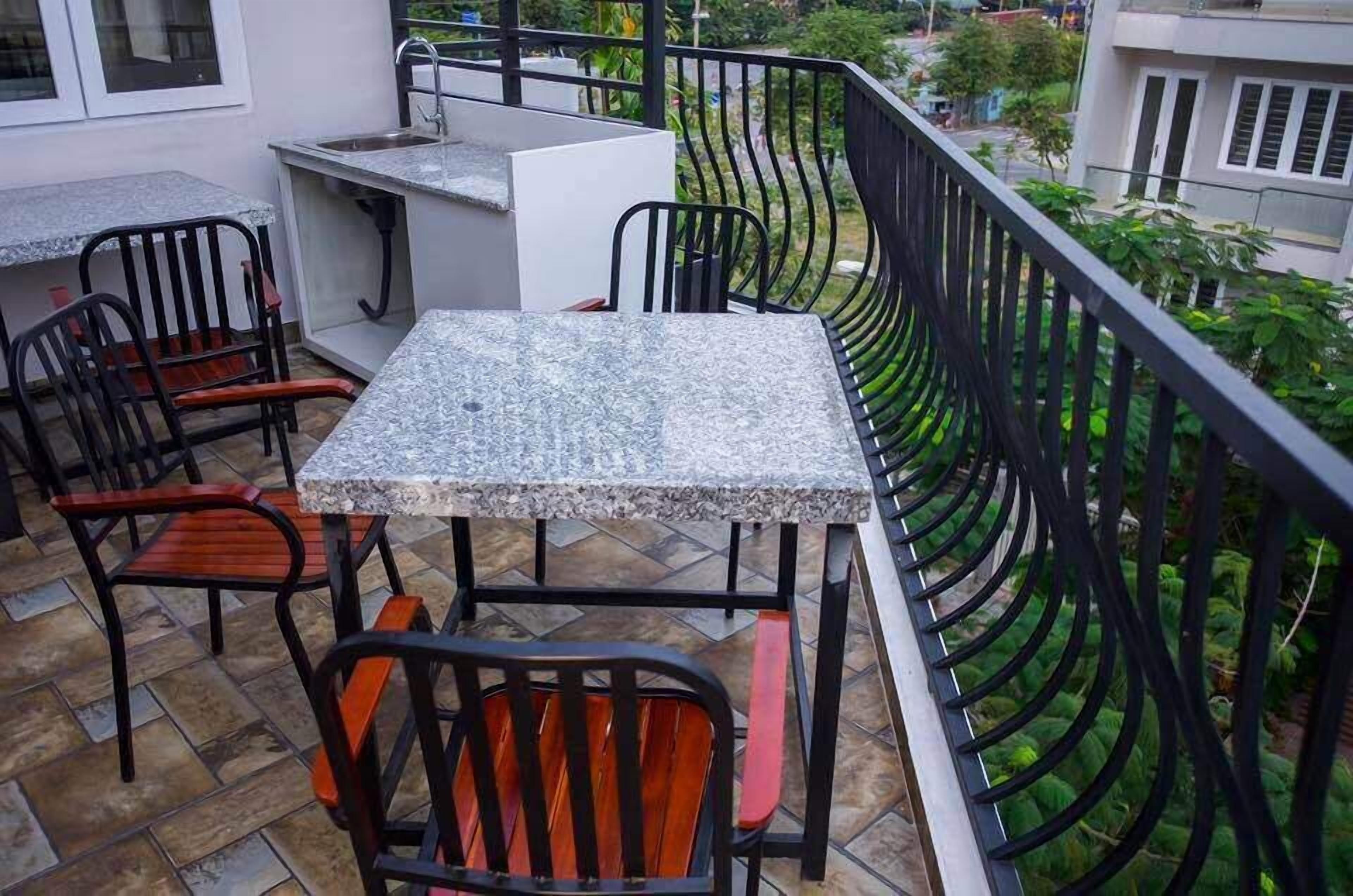 Un balcon avec une table et des chaises, un évier et une vue sur les bâtiments et la végétation environnants.