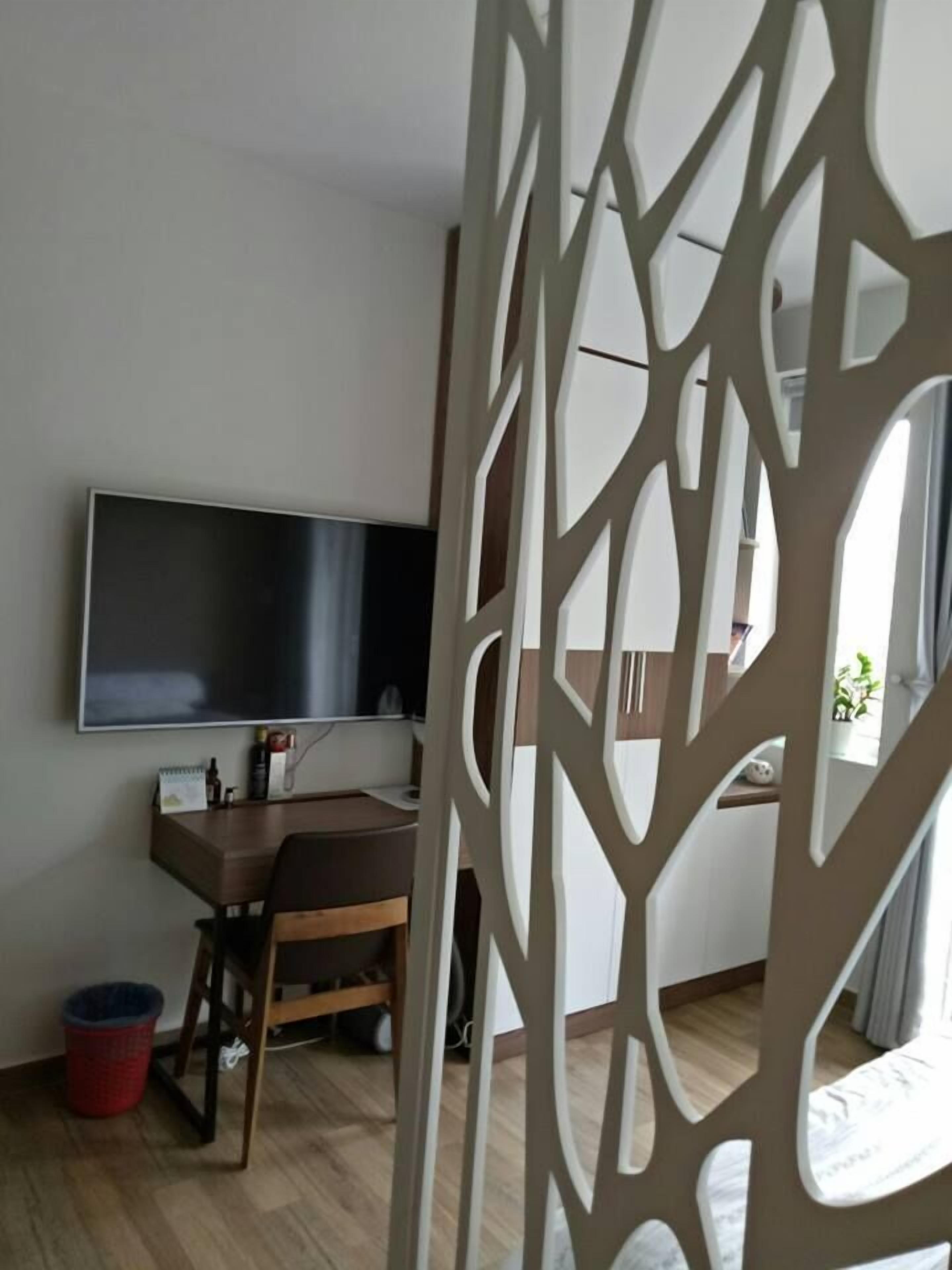 Ein modernes Wohnzimmer mit einem flachbildfernseher an der Wand, einem Holztisch mit Stuhl und einer roten Mülleimer.